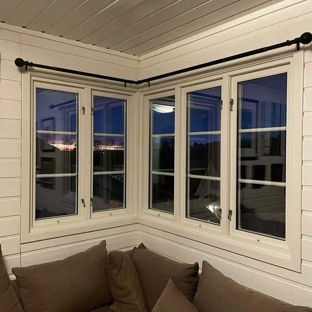 Lyse vegger og store vinduer i en moderne hjørnestue.