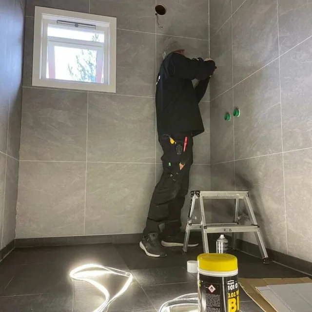 Håndverker i arbeid med flislegging eller membran på et våtrom.